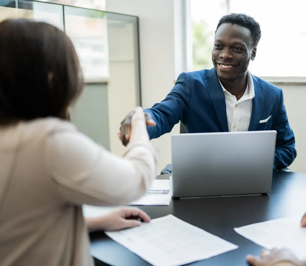 A Black banker shakes hands with a new bank customer.