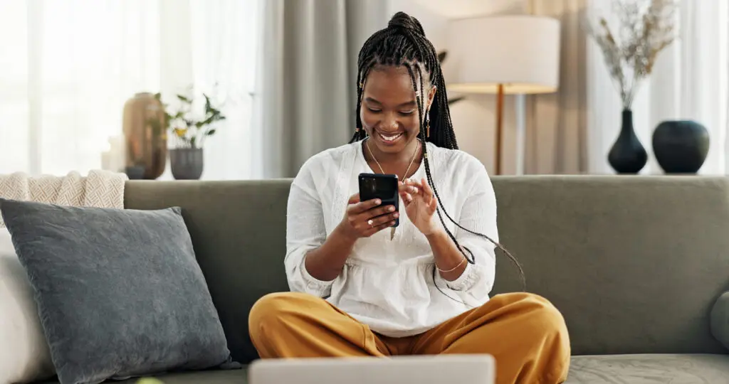 A woman smiles on the couch as she uses Commonwealth National Bank’s digital banking services through their mobile app.