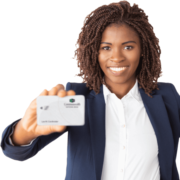 A smiling Black woman in a blue suit is holding up a Commonwealth Bank debit card.