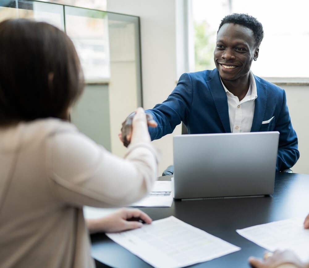 A Black banker shakes hands with a new bank customer.