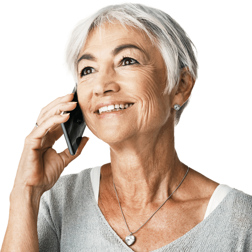 A smiling older woman is holding a smartphone to her ear.
